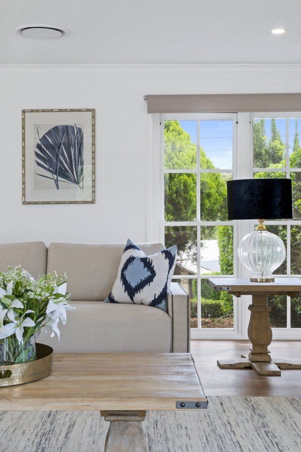 A living room with a couch , table , lamp and window.