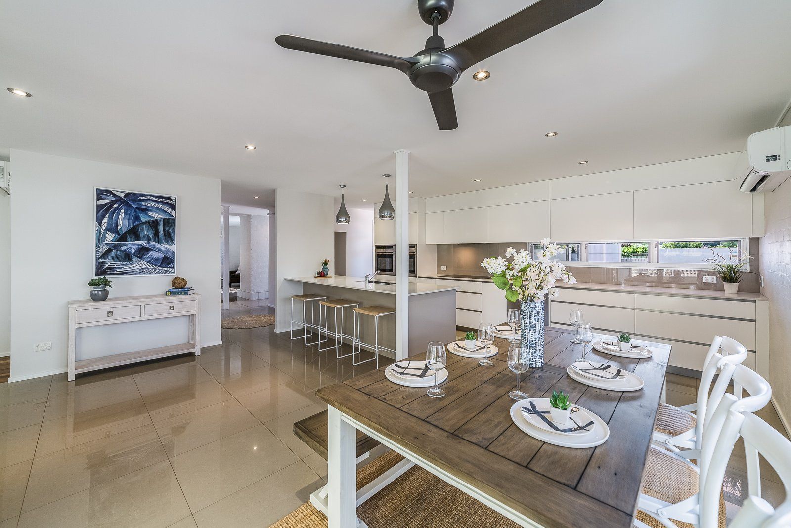 A dining room with a table and chairs and a ceiling fan.