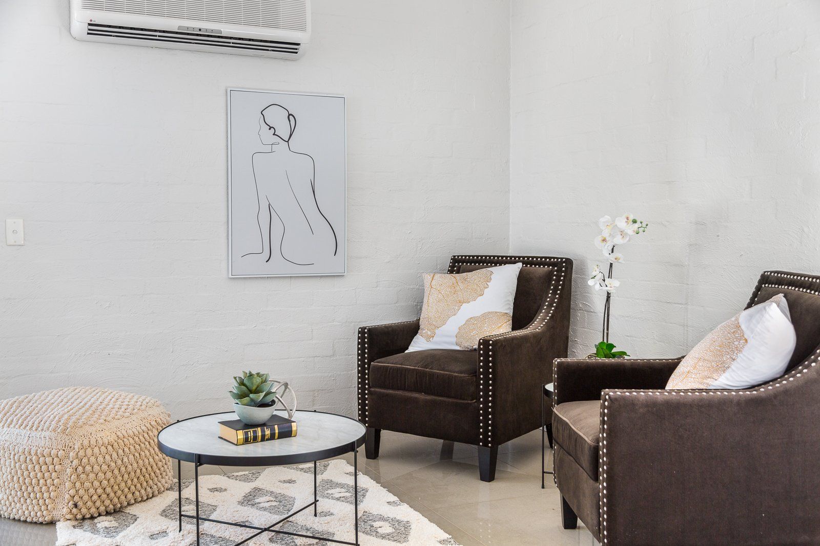 A living room with two chairs , a coffee table , and a painting on the wall.