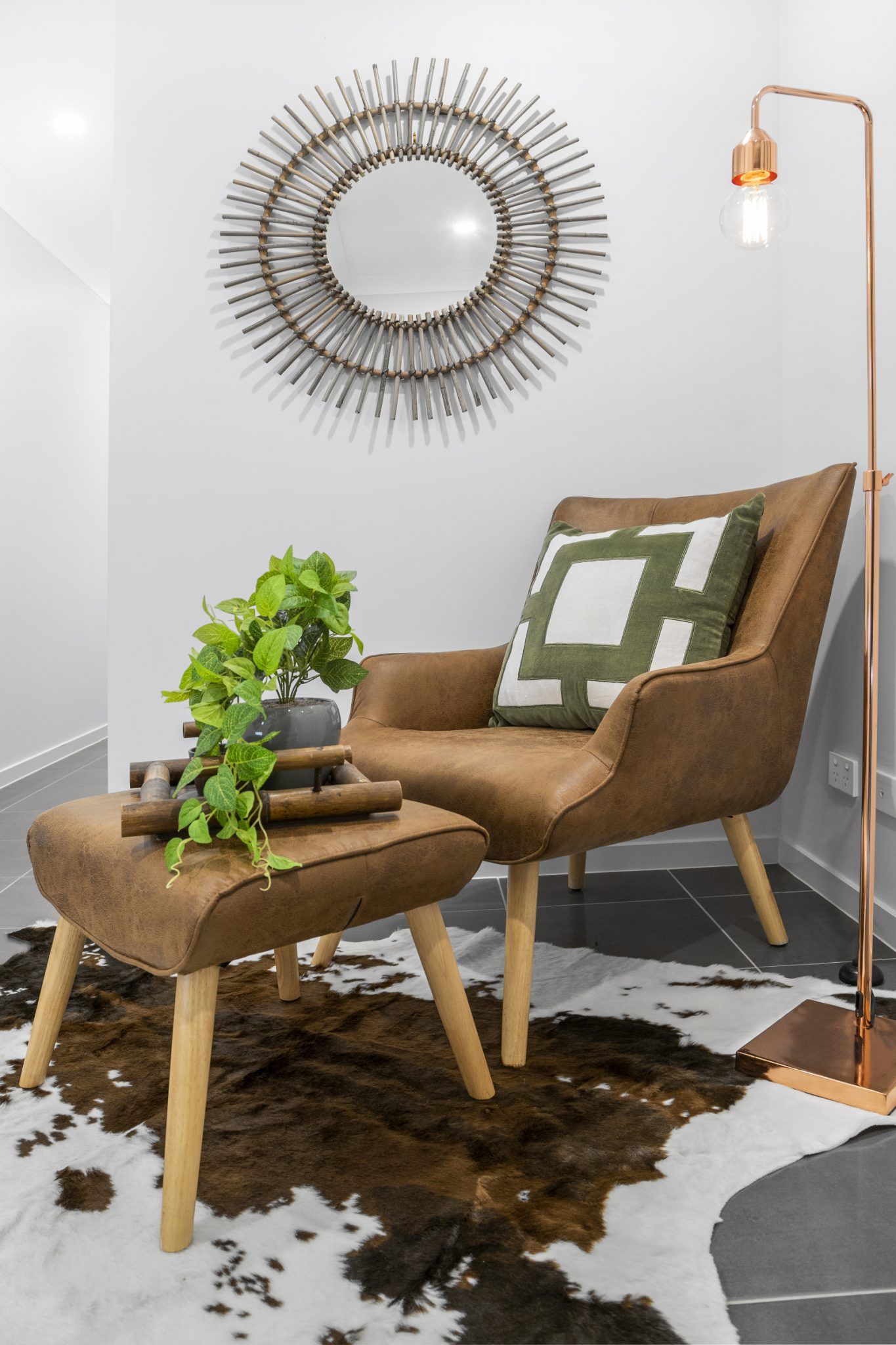 A living room with a chair and ottoman and a mirror on the wall.