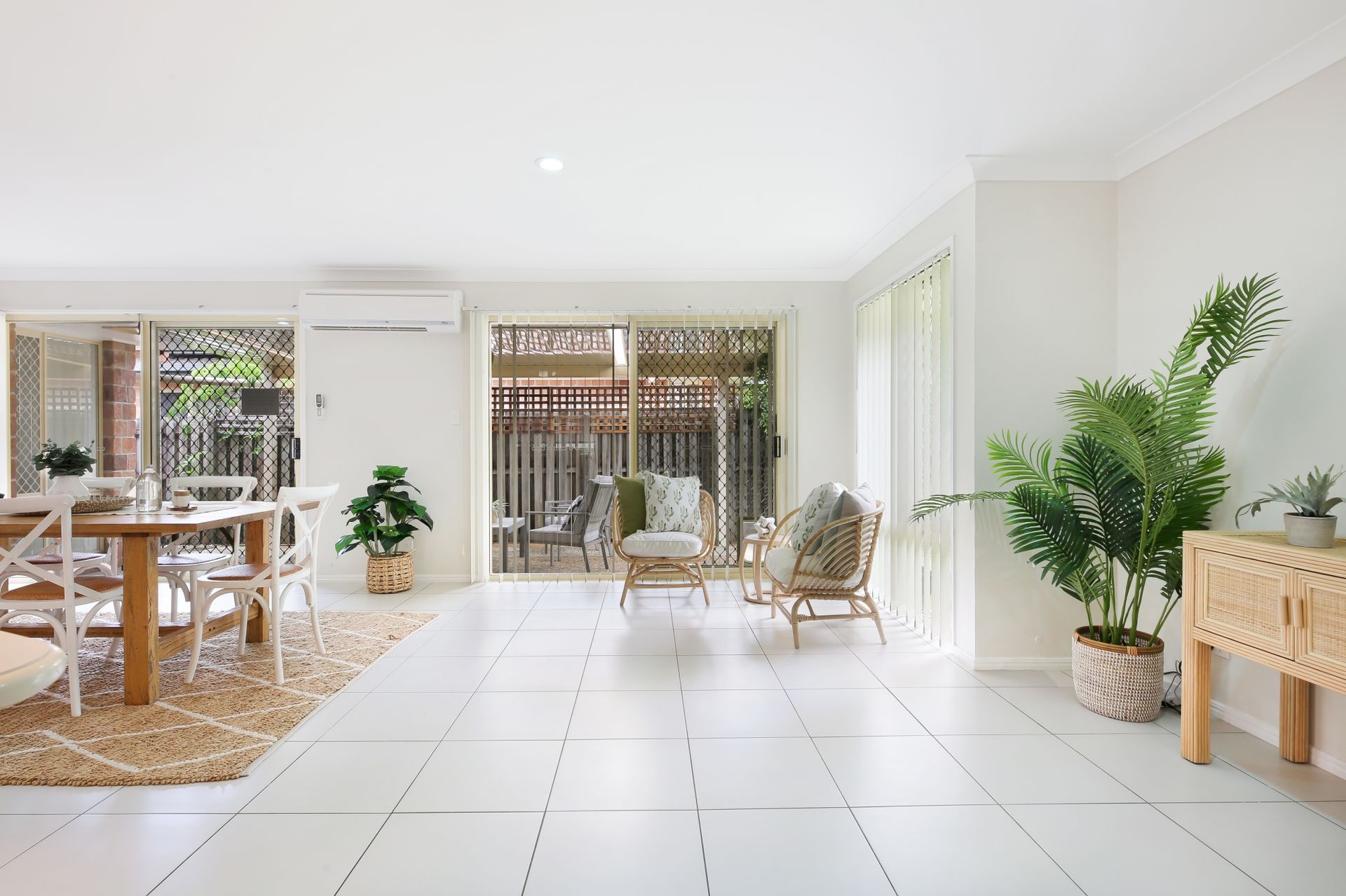 A living room with a dining table , chairs , and plants.