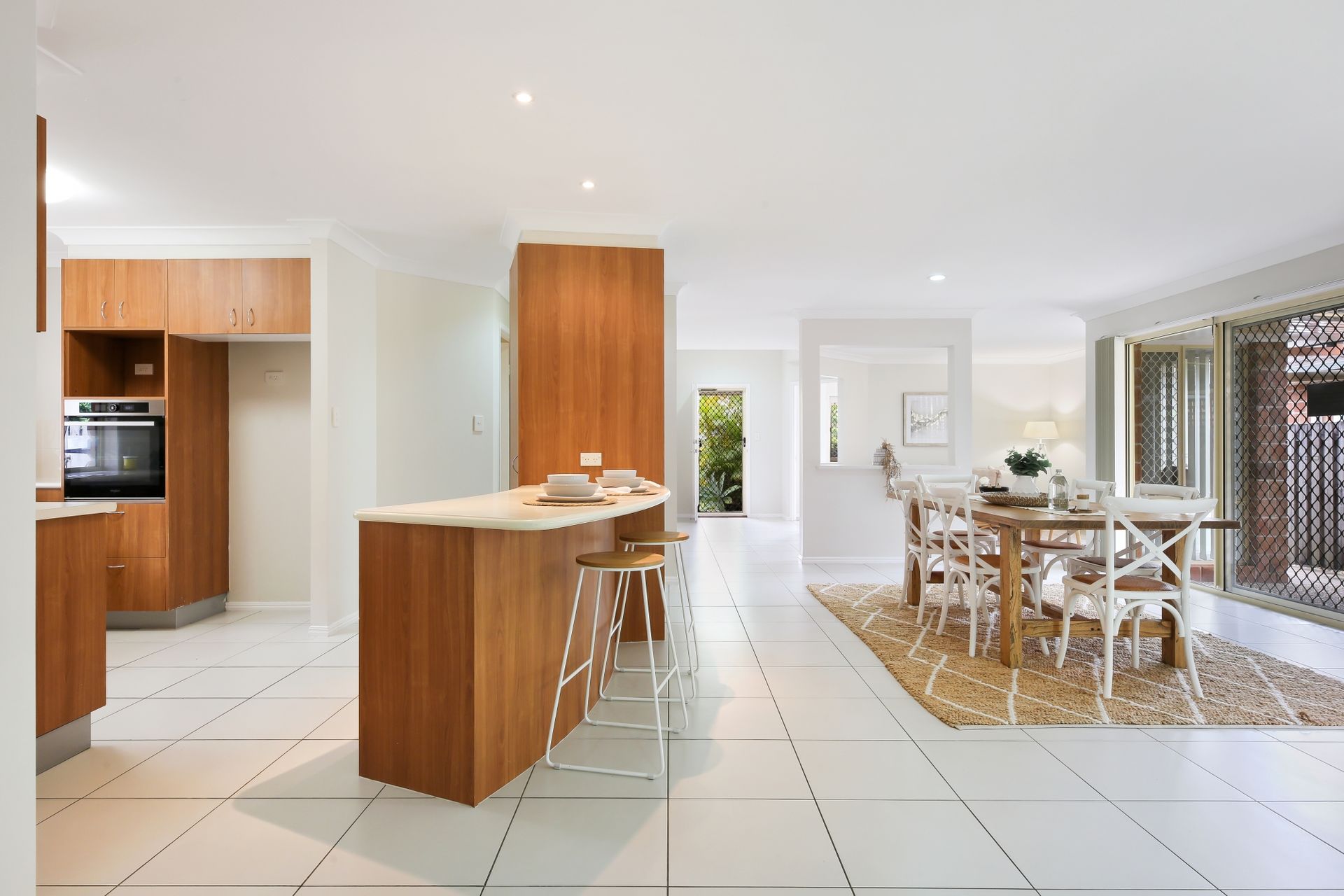 A kitchen and dining room in a house with white tiles