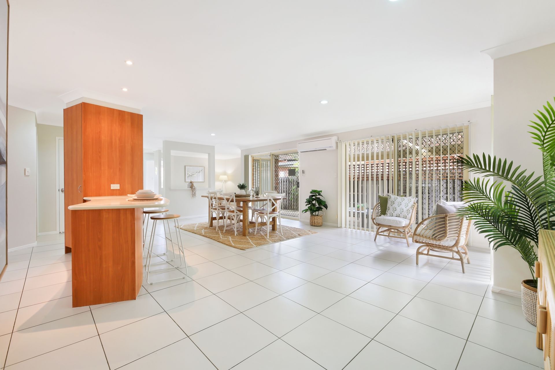 A large living room with white tile floors and a wooden table and chairs.
