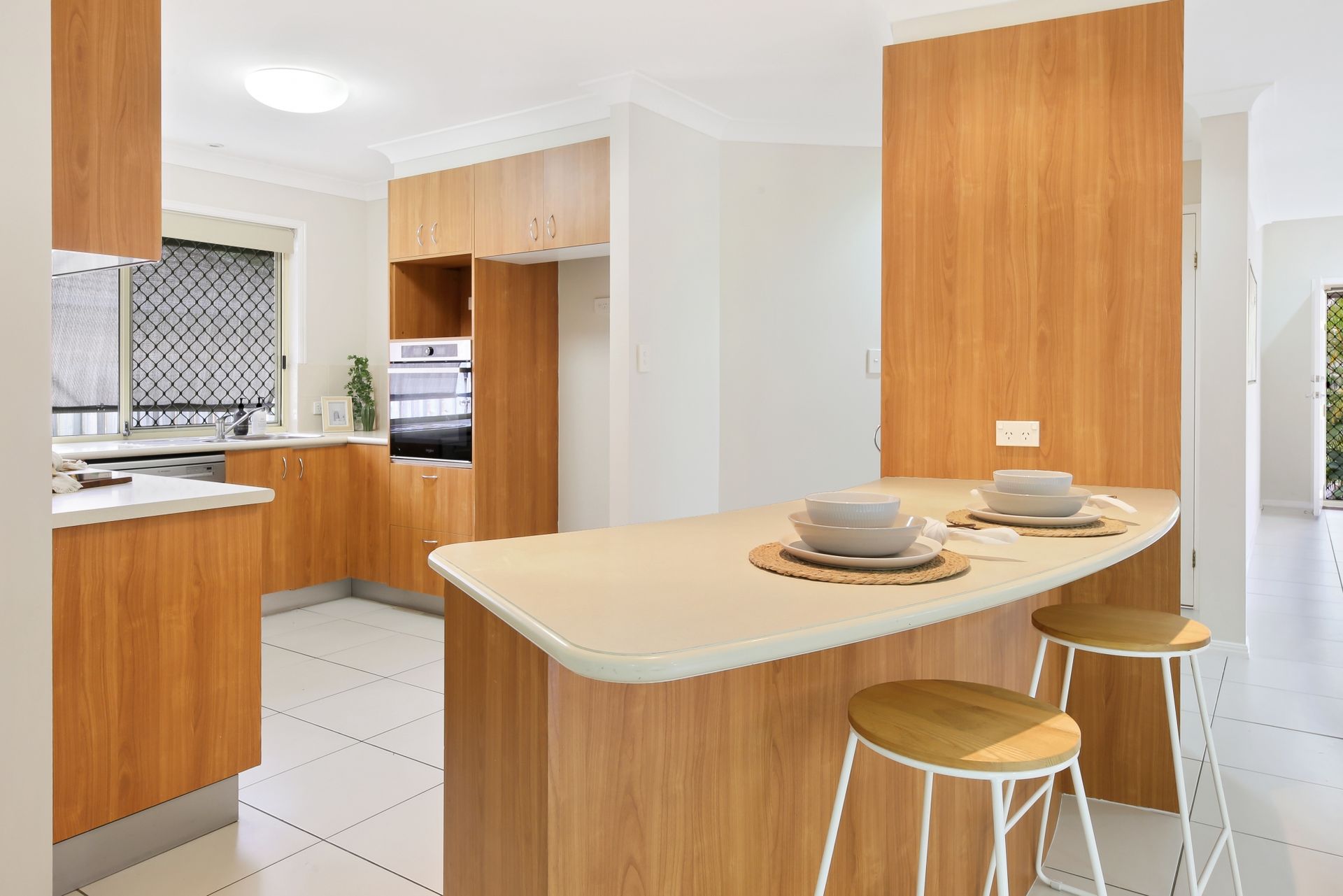 A kitchen with wooden cabinets and stools and a large island.