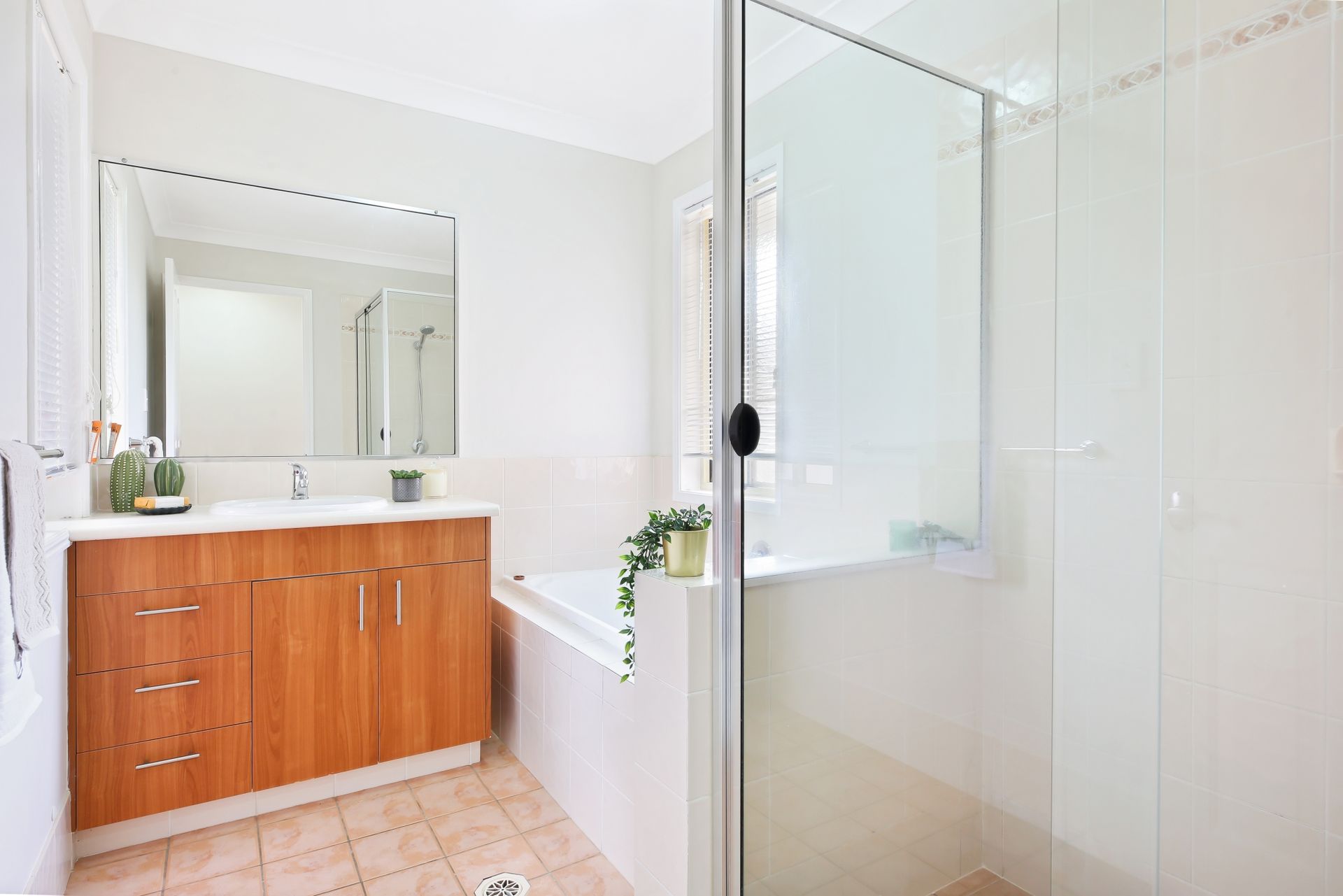 A bathroom with a tub , sink , mirror and shower.