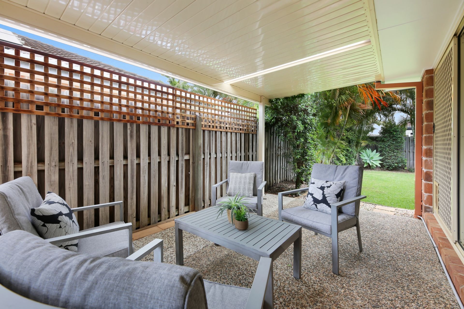 A patio with a couch , chairs and a table under a canopy.
