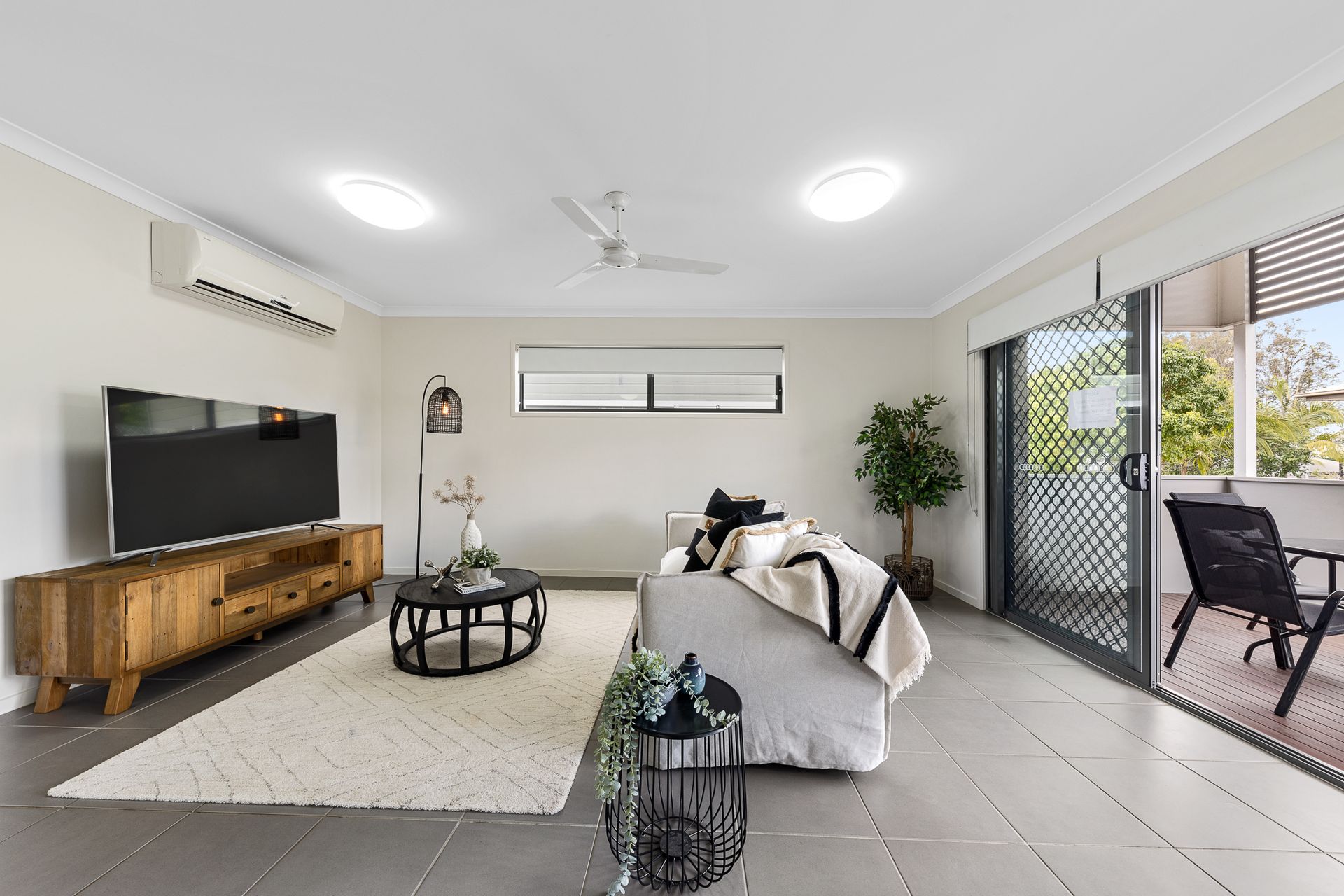 A living room with a couch , table , television and a ceiling fan.