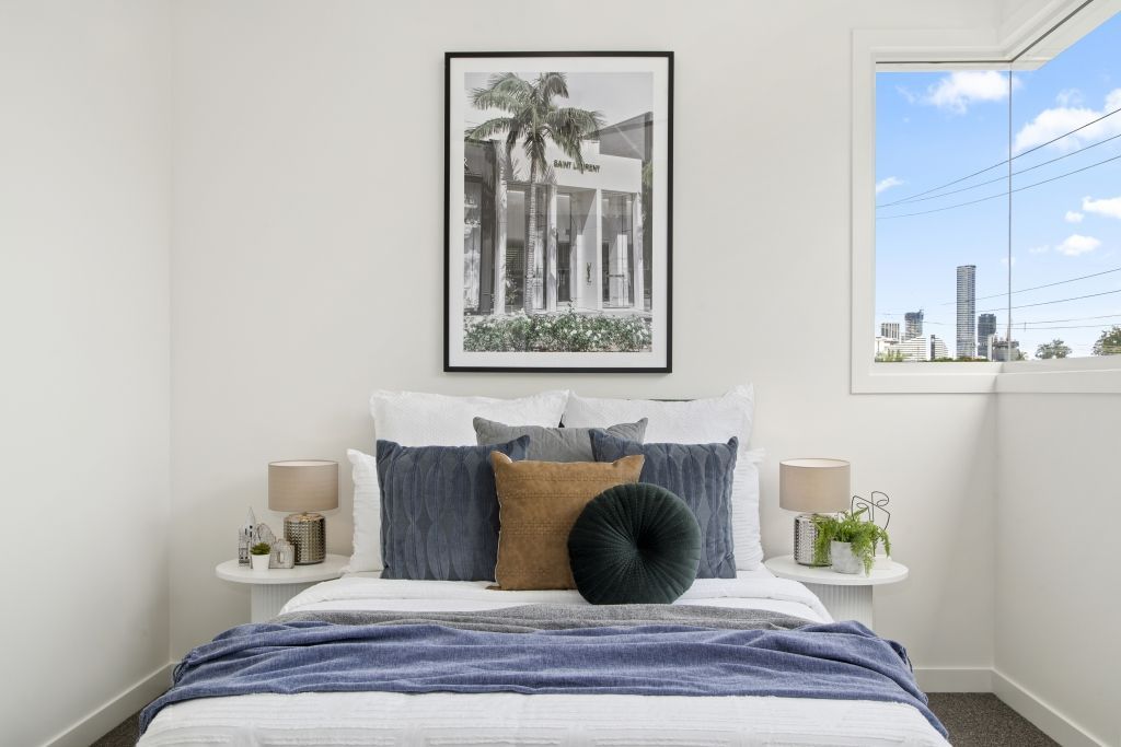 A bedroom with a bed , lamps , a picture on the wall and a window.