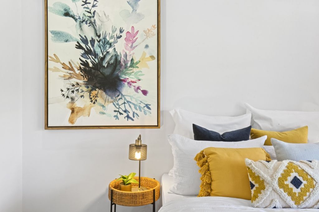 There is a painting on the wall above the bed.