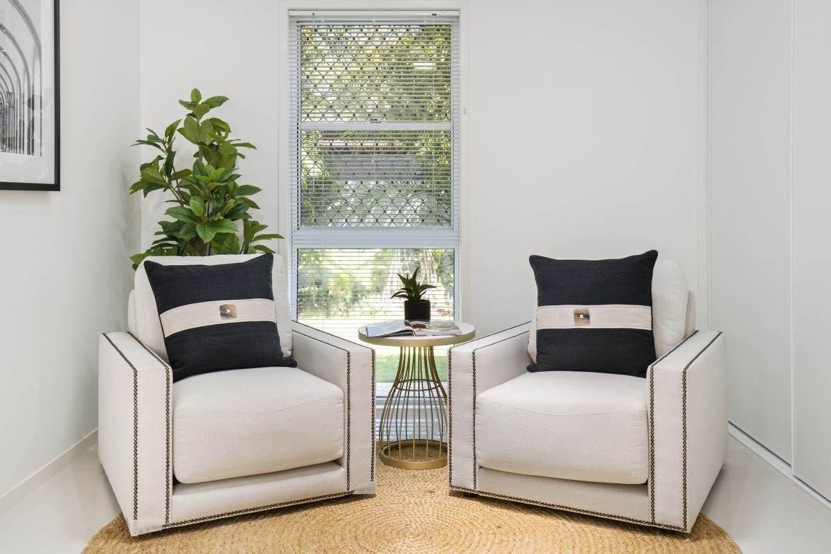 A living room with two chairs and a table in front of a window.