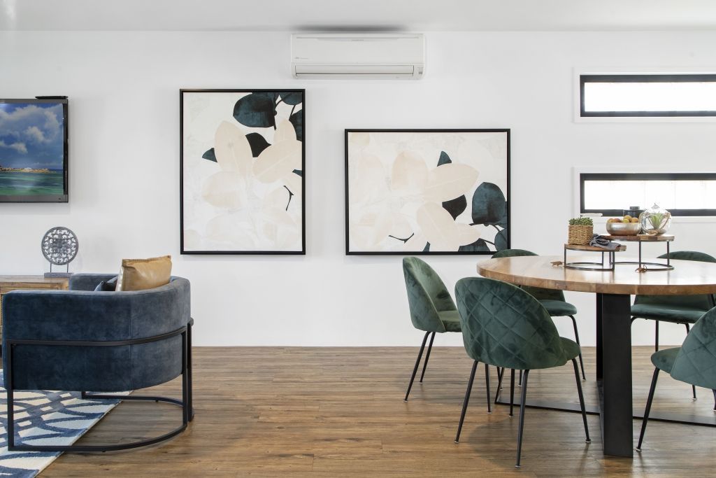 A living room with a dining table and chairs and paintings on the wall.