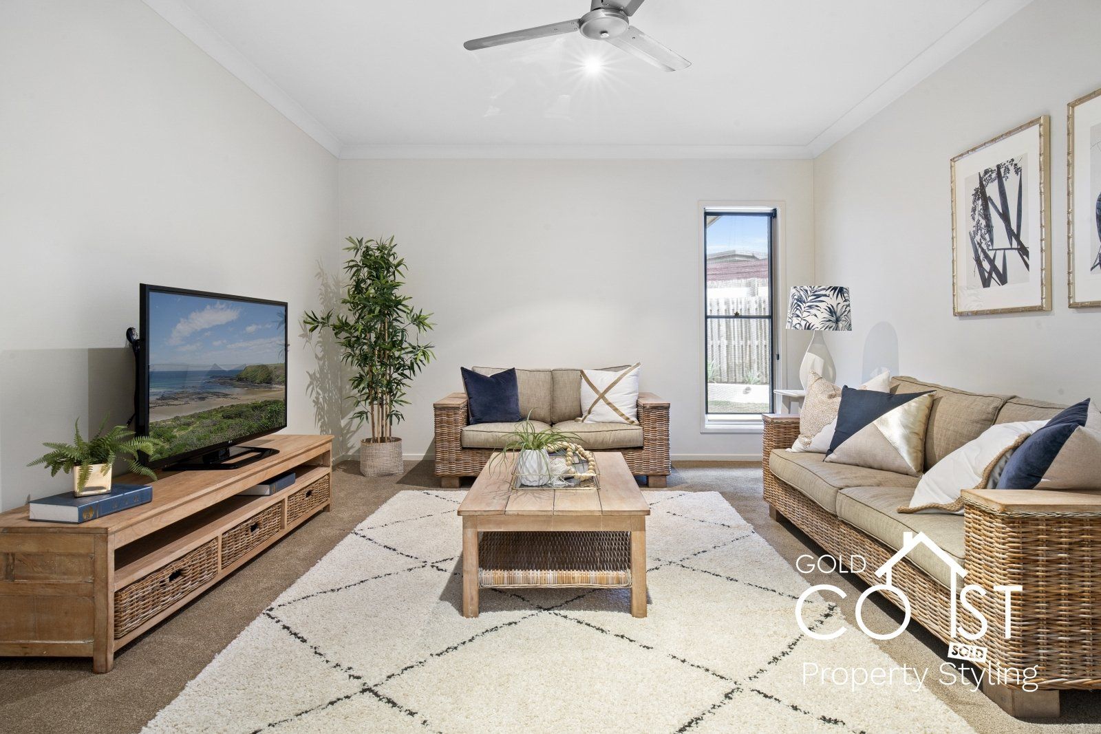 A living room with a couch , table , television and ceiling fan.
