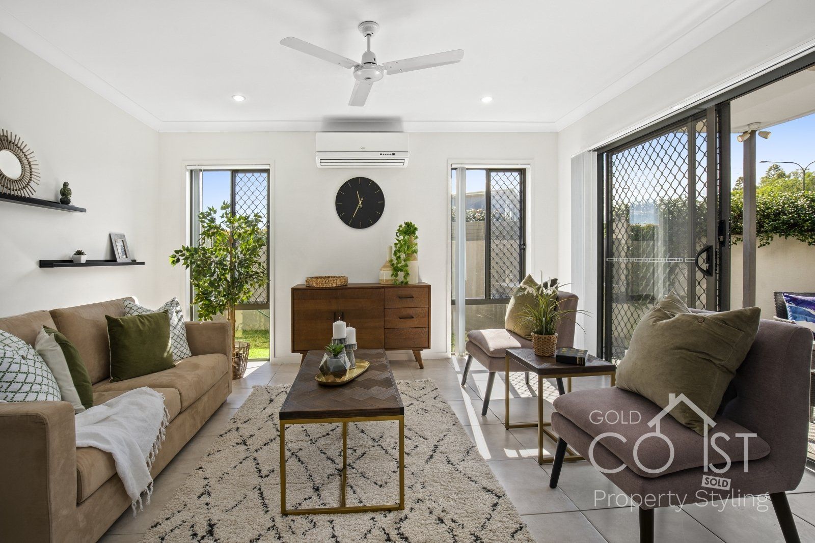 A living room with a couch and chairs and a ceiling fan