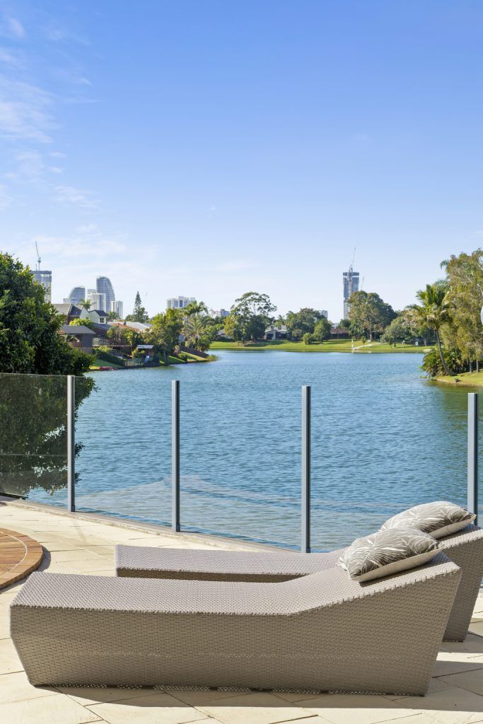 Two lounge chairs are sitting on a patio overlooking a lake.