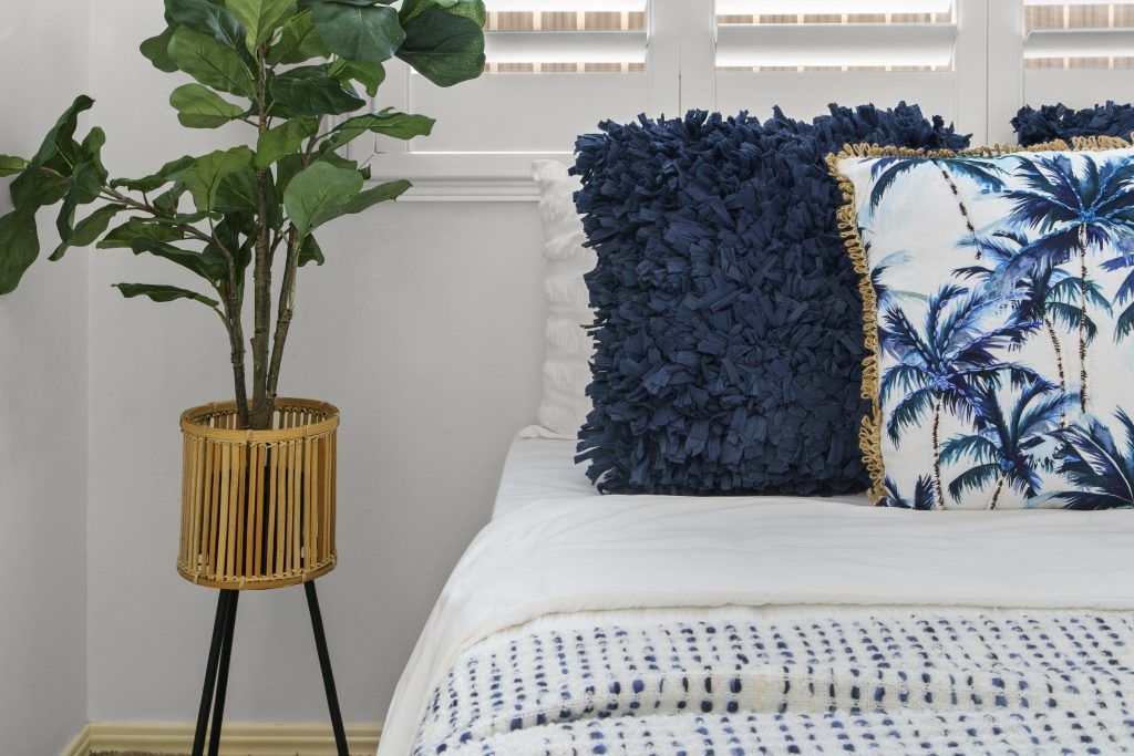 A bedroom with a bed , pillows , and a plant.