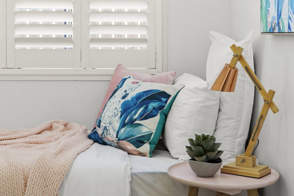 A bedroom with a bed , table , lamp and pillows.