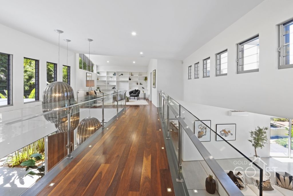 A very long hallway with wooden floors and a glass railing