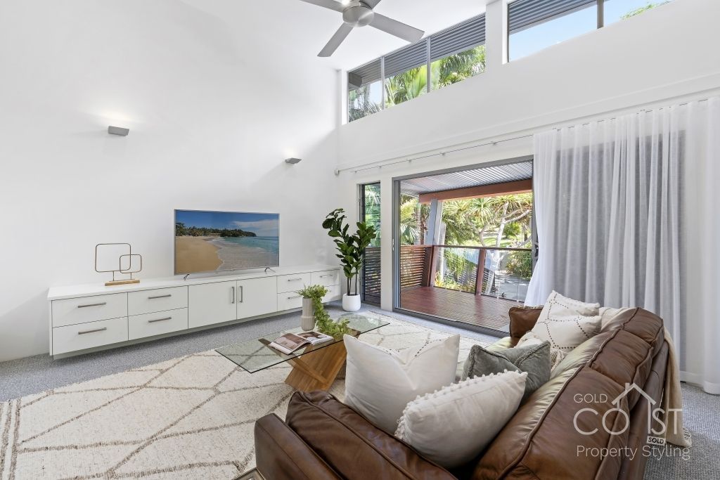 A living room with a brown couch and a ceiling fan.