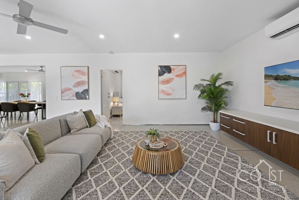 A living room with a couch and a rug and a ceiling fan.
