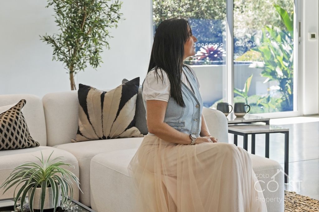 A woman is sitting on a couch in a living room.