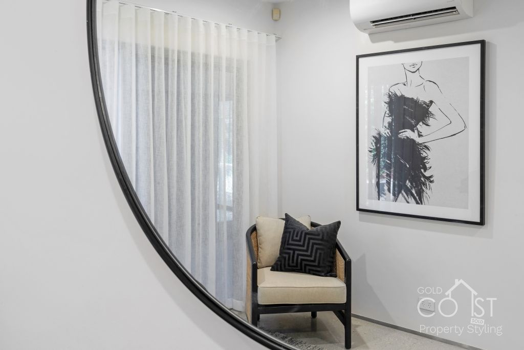 A chair is sitting in front of a large mirror in a room.