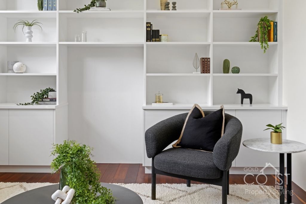A living room with a chair , table , and shelves.