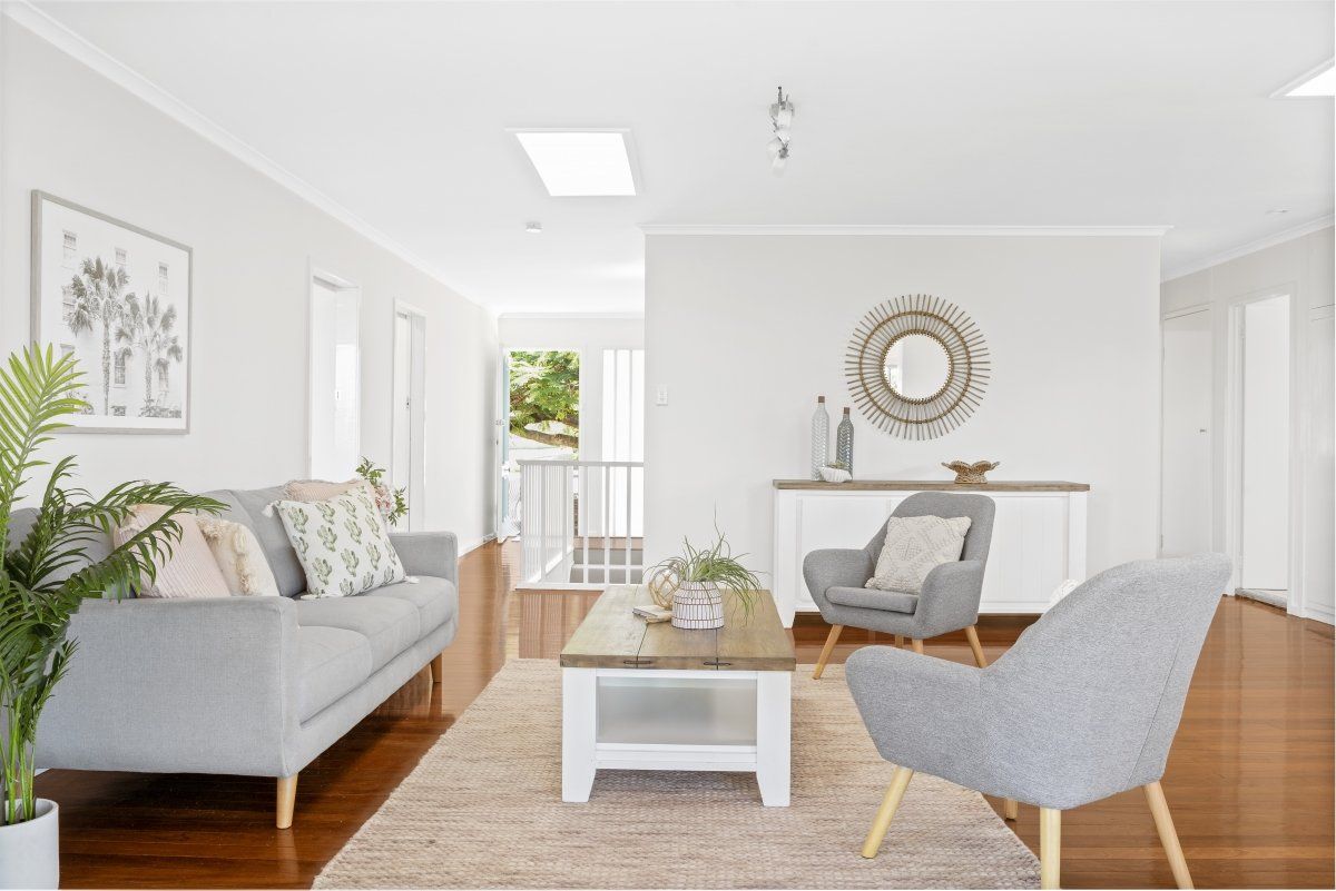A living room with a couch , chairs , and a coffee table.