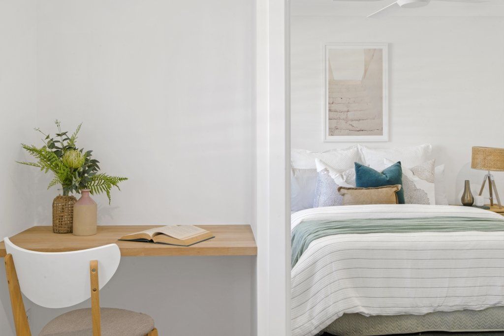 A bedroom with a desk and chair next to a bed.