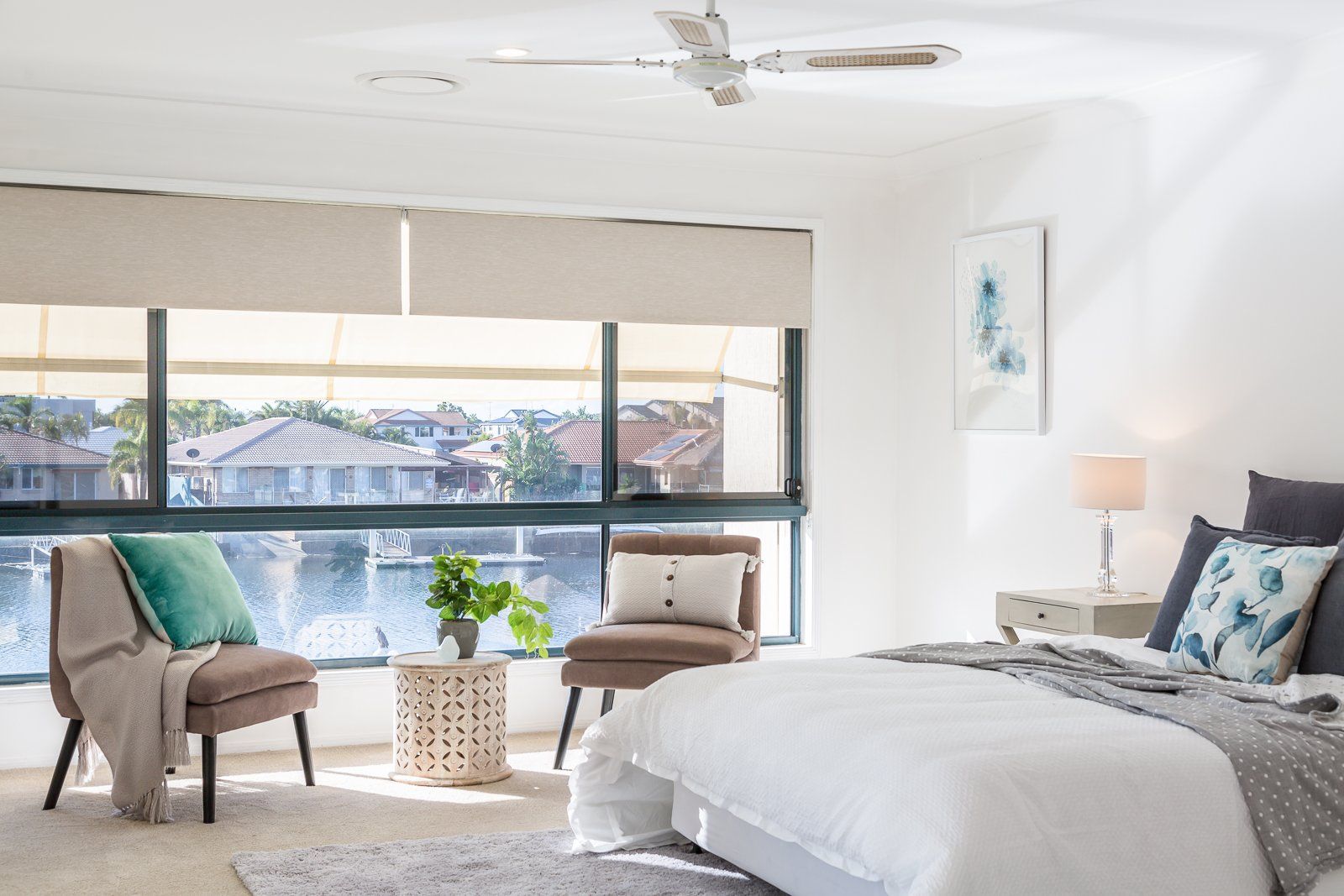A bedroom with a bed , chairs and a ceiling fan.
