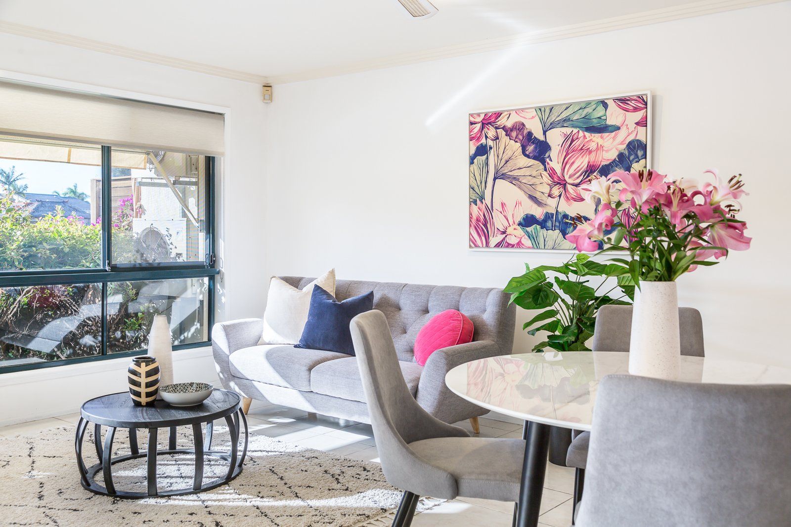 A living room with a couch , chairs , a table and a painting on the wall.