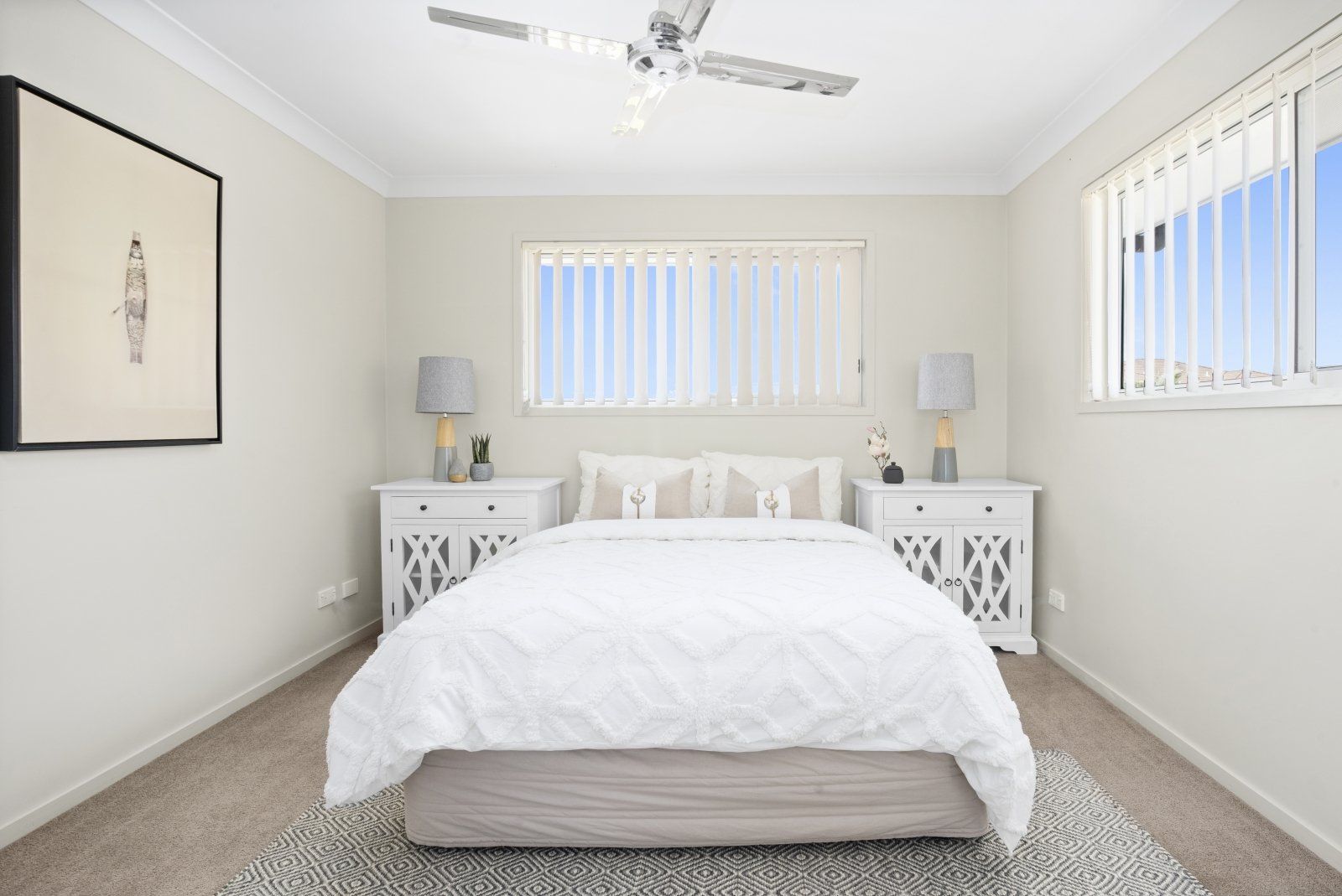 A bedroom with a bed , nightstands , lamps and a ceiling fan.