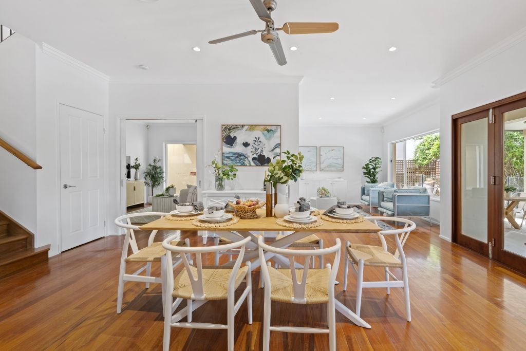 A dining room with a table and chairs and a ceiling fan.