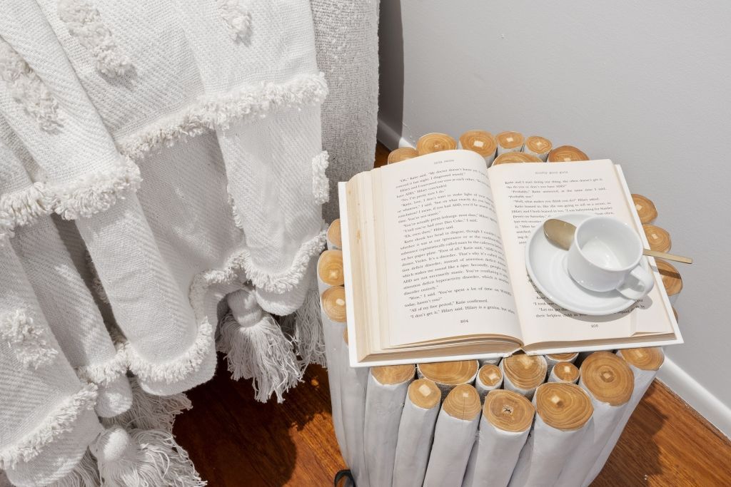 A book is sitting on top of a wooden table next to a cup of coffee.
