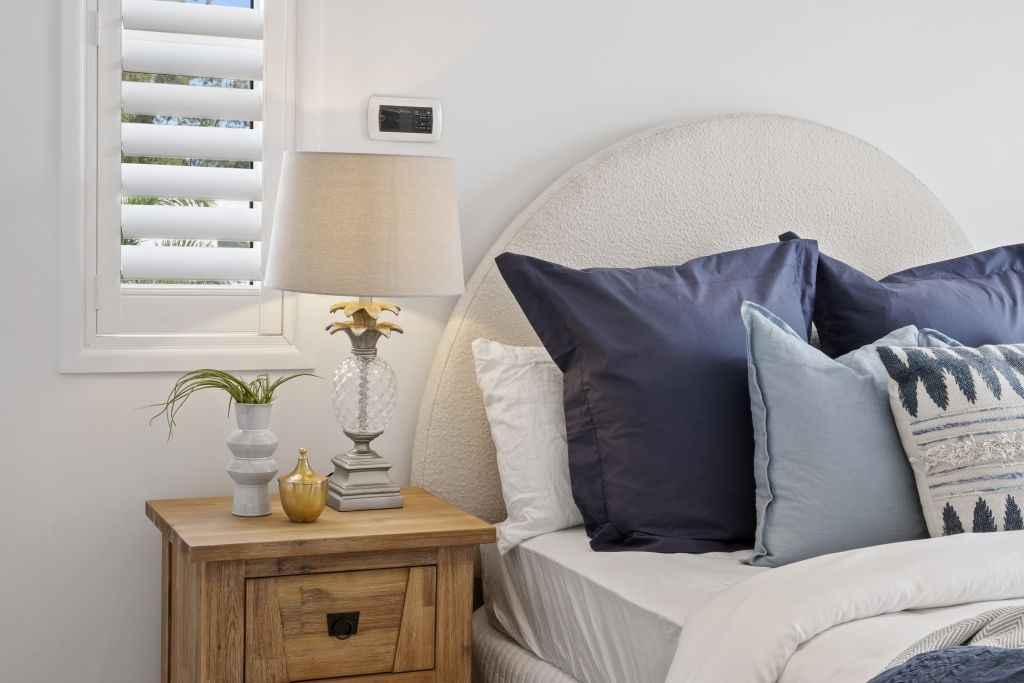 A bedroom with a bed , nightstand , lamp and window.