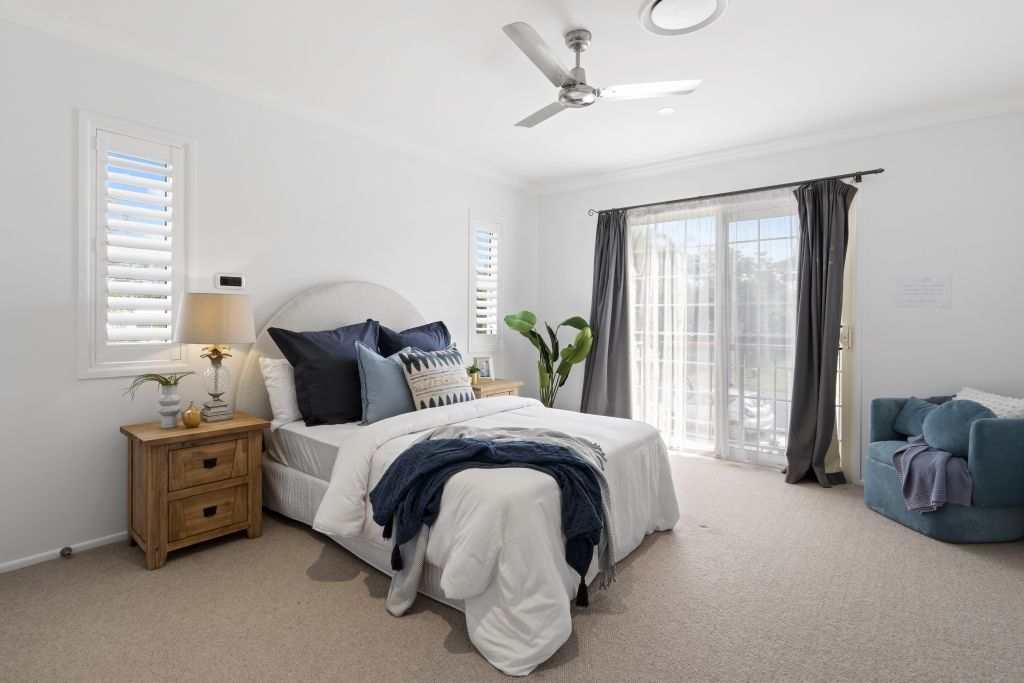 A bedroom with a bed , nightstand , and ceiling fan.