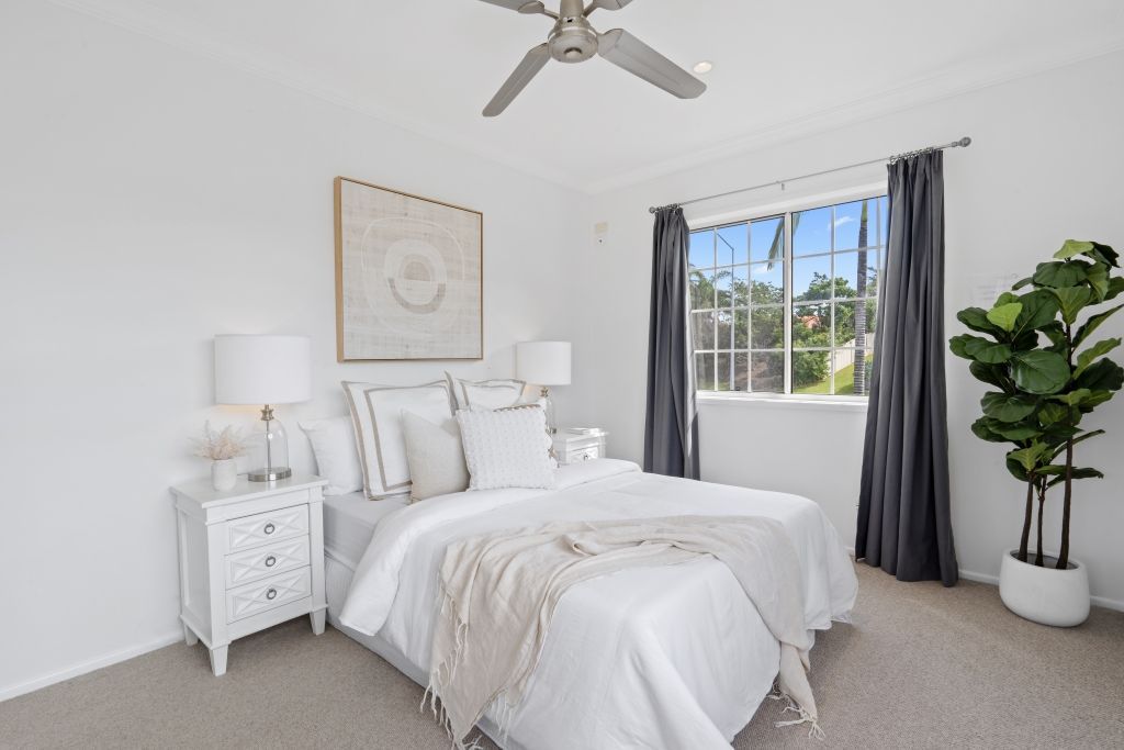 A bedroom with a bed , nightstand , and ceiling fan.