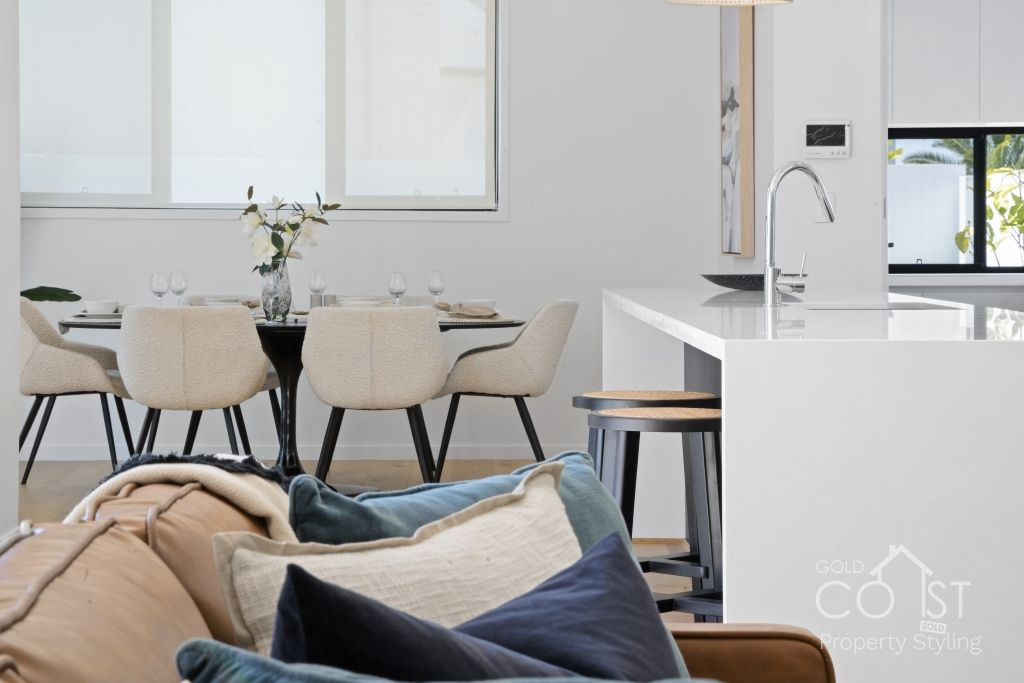 A living room with a couch and pillows and a dining room in the background.