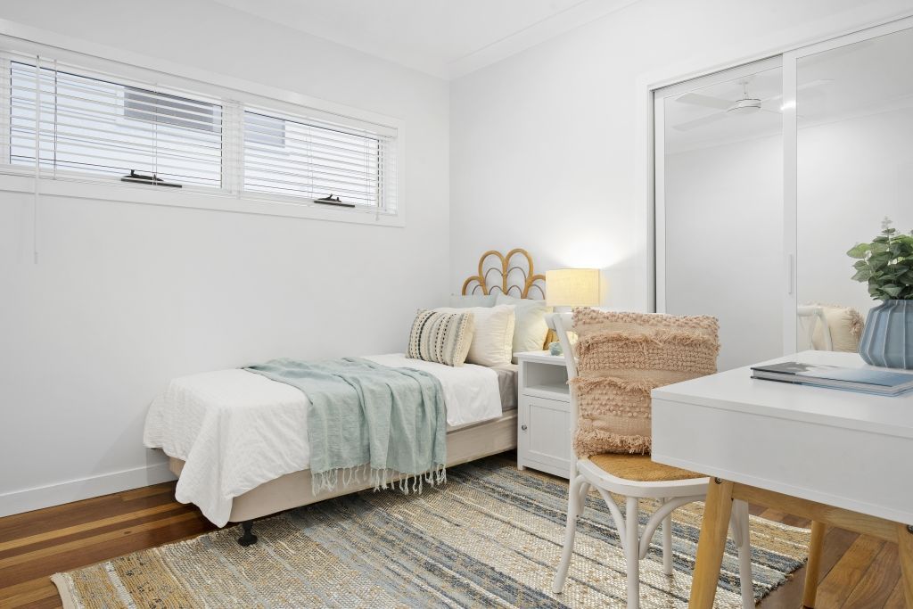 A bedroom with two beds , a desk , and a rug.