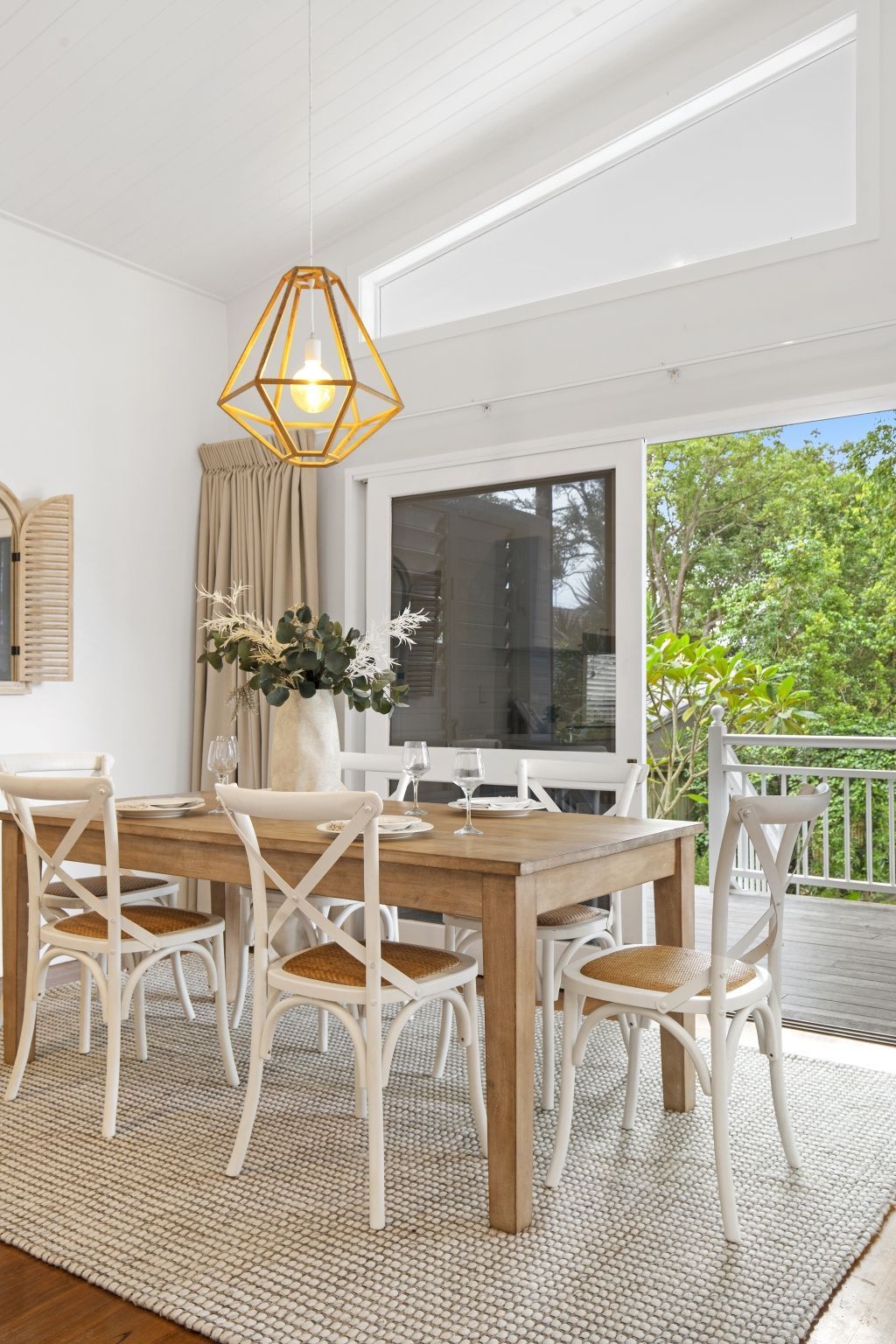 A dining room with a wooden table and chairs and a rug.