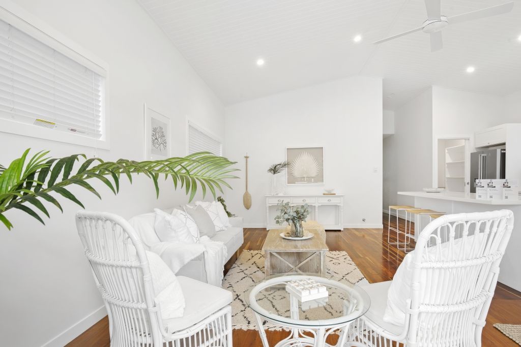 A living room with white furniture , a couch , chairs , and a coffee table.