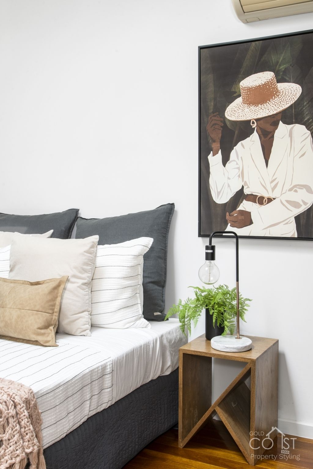 A bedroom with a bed , nightstand , and a painting on the wall.