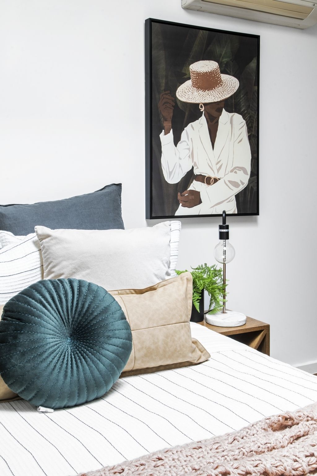 A bedroom with a bed , pillows and a painting on the wall.