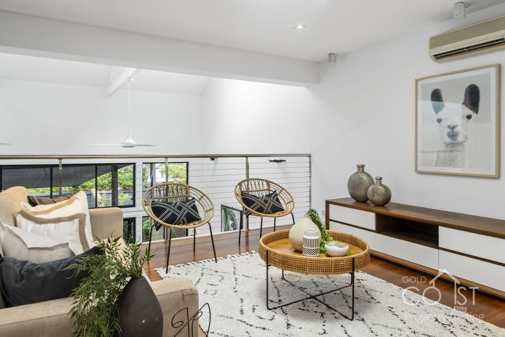 A living room with a couch , chairs , a coffee table and a painting on the wall.