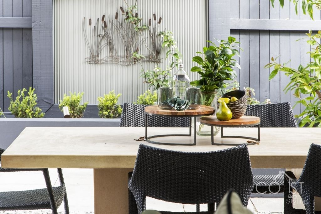 A patio with a table and chairs and a fence in the background.