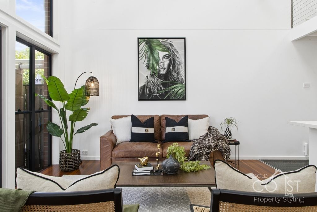 A living room with a couch , chairs , coffee table and a painting on the wall.