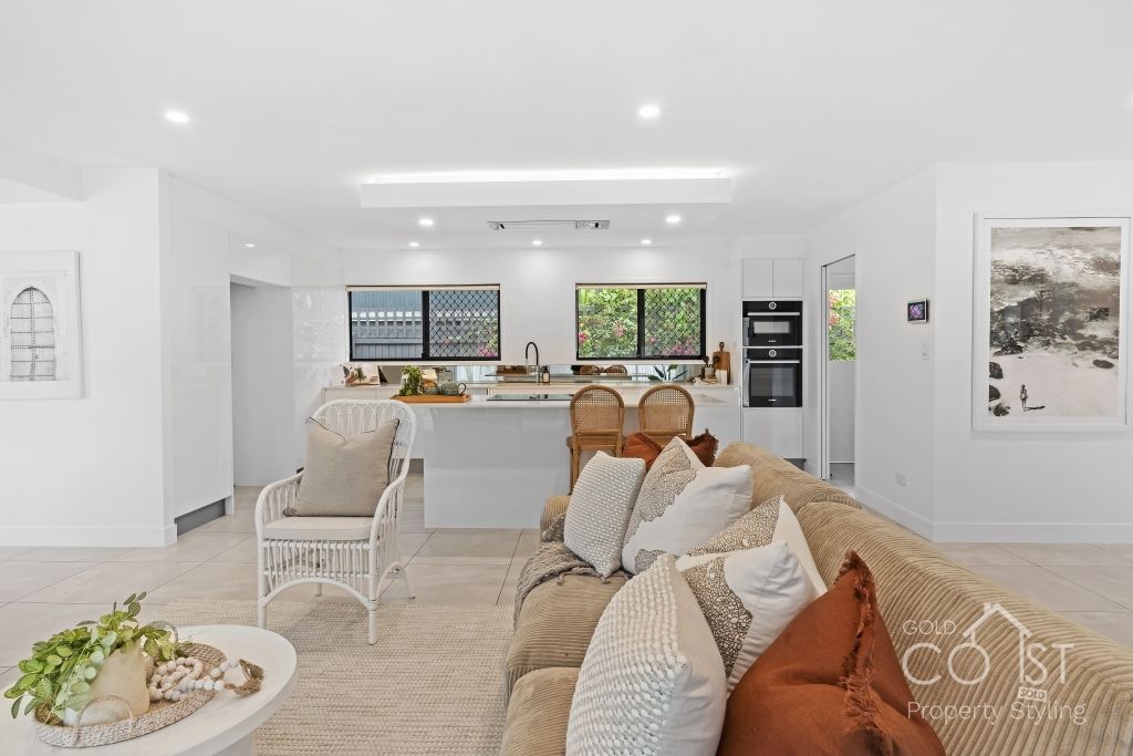 A living room with a couch and chairs and a kitchen in the background.