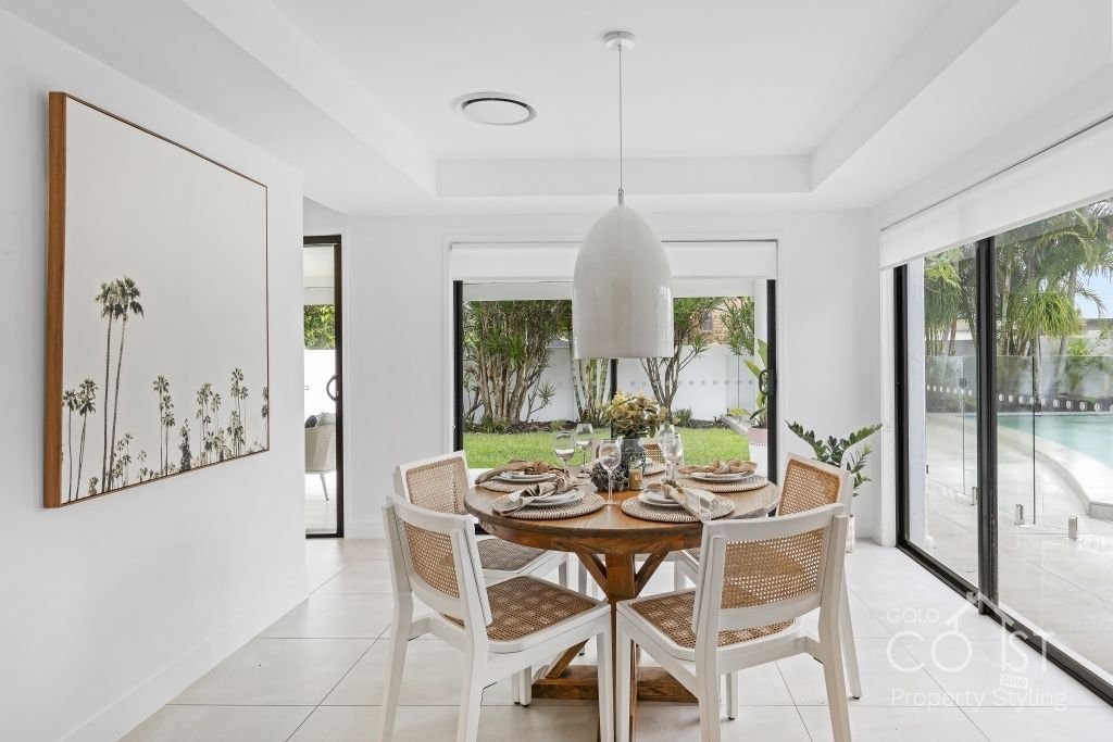 A dining room with a table and chairs and a painting on the wall.