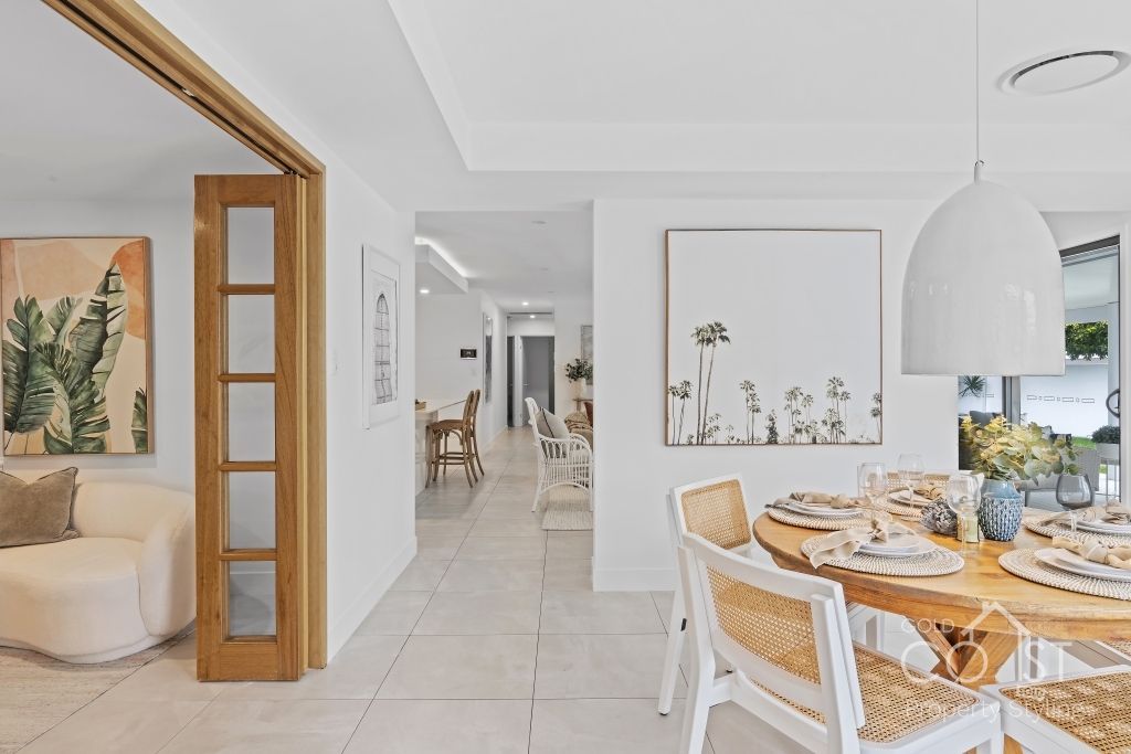 A dining room with a table and chairs and a painting on the wall.