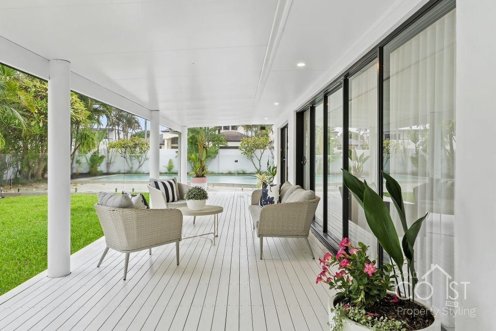 A large white porch with chairs and a potted plant.