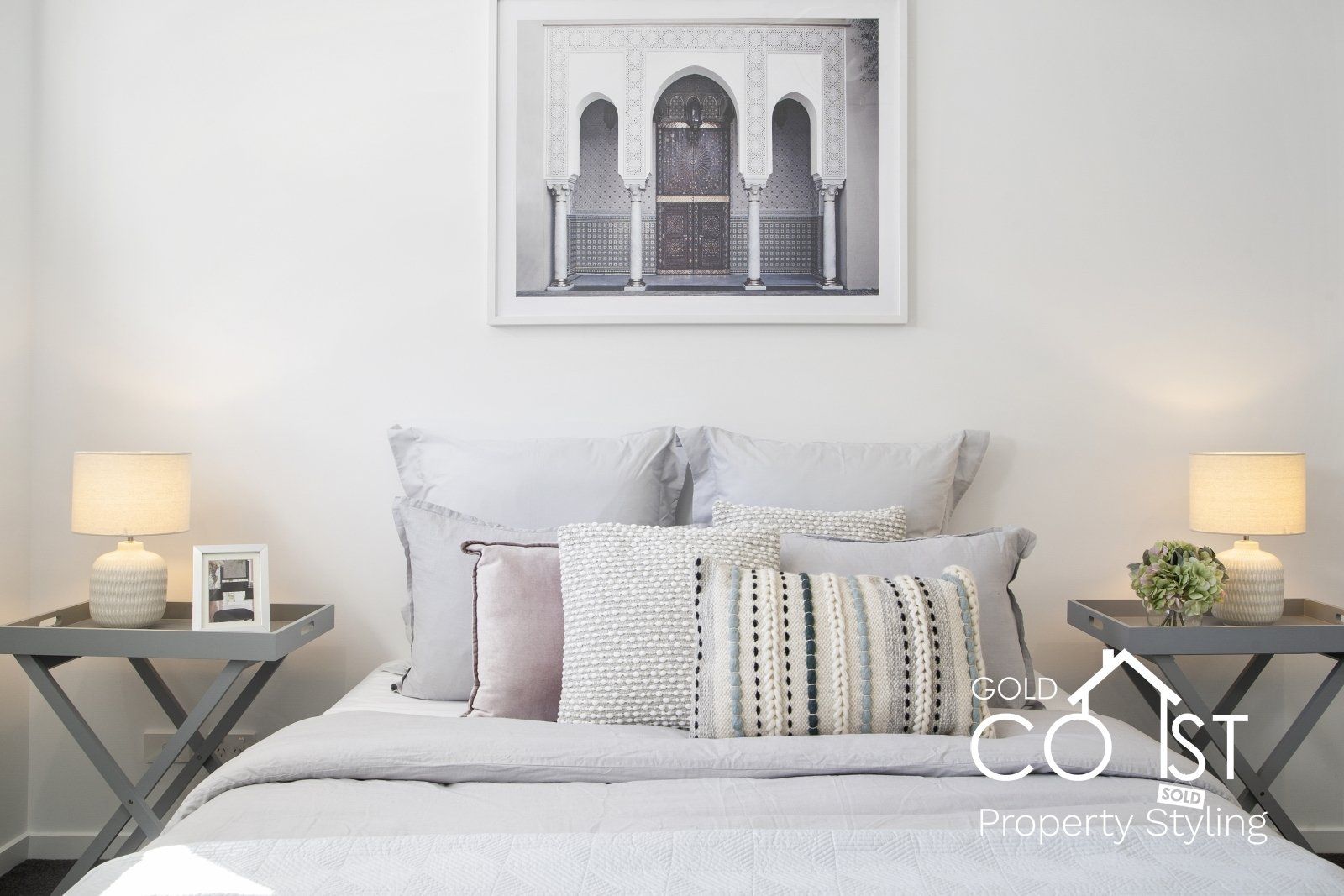 A bedroom with a bed , nightstands , lamps and a picture on the wall.